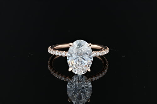 Oval brilliant cut diamond solitaire engagement ring with pave set round brilliant cut diamonds