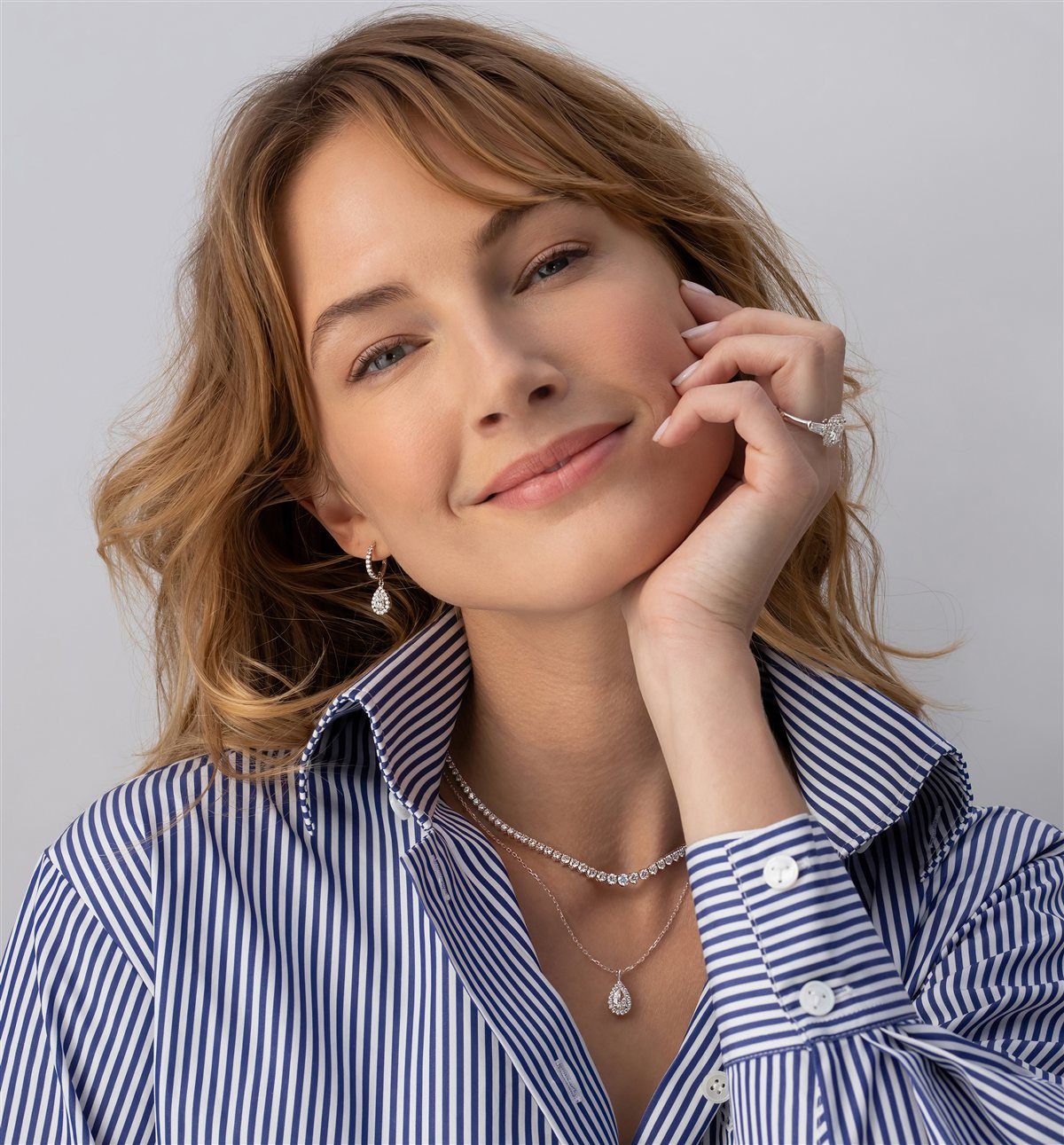 Woman wearing a diamond engagement ring, pear drop earrings and tennis necklace, Nathan Alan Jewelers Newport Beach